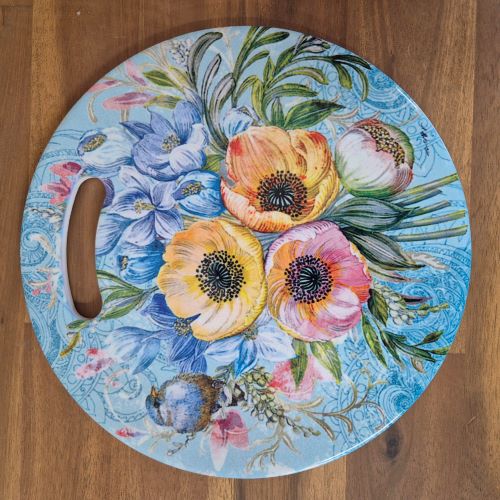 Protect your table and add a touch of nature with our Garden Flower Blue Bird Kitchen Trivet. Made of ceramic, this trivet features a beautiful blue bird and garden image, providing a functional and decorative addition to your kitchen. Keep your table safe while adding a touch of beauty.  Round | Ceramic | Gloss finish | Cork non slip backing | Diameter 20 cm | Design available in coasters & serving tray.