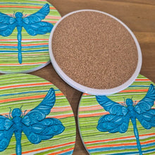 Load image into Gallery viewer, Add a touch of nature to your table with our Dragonfly Coasters! This set of 4 round coasters features beautiful and colourful dragonflies, adding a pop of color to any table. Protect your surfaces while also adding a stylish and unique touch to your home decor.  Colourful as shown | Round | 10 cm diameter | Set of 4 - same design | White gift box with lid | Glossy finish | Cork non slip backing.&nbsp;