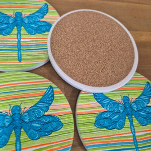 Add a touch of nature to your table with our Dragonfly Coasters! This set of 4 round coasters features beautiful and colourful dragonflies, adding a pop of color to any table. Protect your surfaces while also adding a stylish and unique touch to your home decor.  Colourful as shown | Round | 10 cm diameter | Set of 4 - same design | White gift box with lid | Glossy finish | Cork non slip backing.&nbsp;