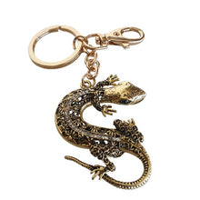 Load image into Gallery viewer, Add a touch of good luck to your everyday life with our Gecko Keyring Gift. Made of silver and blue metal, this keychain features a charming gecko design, symbolizing good fortune and prosperity. Carry it with you or gift it to a loved one for a daily reminder of luck and blessings.  Gecko 5 x 6 cm | Gold metal keychain -&nbsp; full length 12 cm |&nbsp;&nbsp;Blue rhinestones | Comes in a beautiful cotton organza gift bag - colours will vary