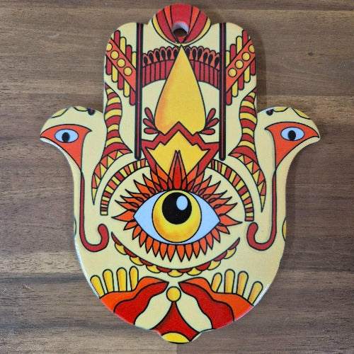 This multi-functional Hamsa Hand Of Protection serves as a trivet, plate, and hanging sign. Made from colorful ceramic, it adds a touch of charm to any kitchen or room. The Hamsa hand symbol offers protection and good luck, making it a meaningful and thoughtful gift.  In all faiths it is a protective sign. It brings it's owner happiness, luck, health, and good fortune.