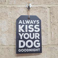 Load image into Gallery viewer, how your love for your furry friend with our &quot;Always Kiss Your Dog Goodnight&quot; ceramic plaque. A perfect gift for any dog lover, this hanging sign serves as a daily reminder to cherish every moment with your four-legged companion. Spread the love and hang this charming plaque in your home.  Black &amp; White | Ceramic | Cork ba