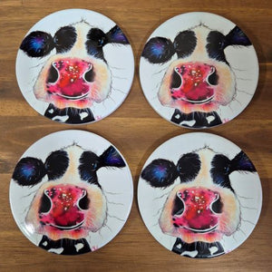 Enhance your bar / table experience with these high-quality Cow Table Bar Coasters. This boxed set of 4 ceramic coasters features a cute and playful cow cartoon image, adding a touch of whimsy to your table. Protect your surfaces while adding a touch of personality to any gathering.  Set of 4 coasters - same image | Round 10 cm diameter | Gloss protective front | Cork non slip backing | Boxed in our white coaster box with lid.