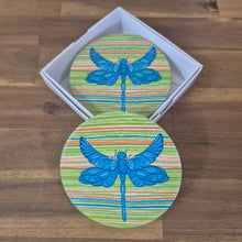 Load image into Gallery viewer, Add a touch of nature to your table with our Dragonfly Coasters! This set of 4 round coasters features beautiful and colourful dragonflies, adding a pop of color to any table. Protect your surfaces while also adding a stylish and unique touch to your home decor.  Colourful as shown | Round | 10 cm diameter | Set of 4 - same design | White gift box with lid | Glossy finish | Cork non slip backing.&nbsp;