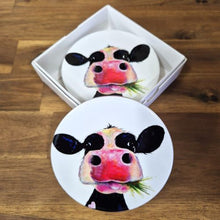 Load image into Gallery viewer, Enhance your table or bar with these adorable Cow Table Bar Coasters. Featuring a cute cartoon cow grazing on grass, this set of four ceramic coasters is the perfect gift for any cow lover. Protect your surfaces while bringing a touch of whimsy to any space.  Set of 4 coasters - same image | Round 10 cm diameter | Gloss protective front | Cork non slip backing | Boxed in our white coaster box with lid.