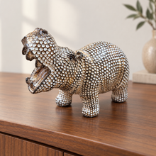Load image into Gallery viewer, A hippopotamus figurine covered in textured metallic studs, standing on a polished wooden cabinet with a softly blurred indoor background.