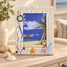 Load image into Gallery viewer, A decorative picture frame with a nautical beach scene insert, styled on a wooden table with shells, a vase, and a sofa in the background.