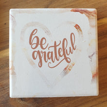 Load image into Gallery viewer, Our beautiful Be Grateful gift set - hanging ceramic plaque &amp; boxed 4 set of coasters.  Coasters diameter - 10cm - Ceramic - Cork backing - Set of 4 - White gift box with lid.  Hanging Plaque - 10 x 15 cm -  Rope hanger - Ceramic - Cork backing   A beautiful gift to give, a beautiful saying and reminder to always be grateful.