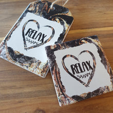 Load image into Gallery viewer, Relax - love heart hanging ceramic plaque and set of 4 boxed quality coasters.  A beautiful gift set for any home or office.  Relax Coasters Diameter - 10cm - Ceramic - Set of four - White gift box with lid - Cork backing - Four of same design as shown in photo.  Relax Hanging Plaque - 10 x 15 cm + Rope hanger -  Ceramic - Cork backing 