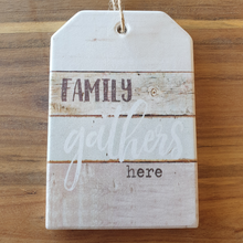 Load image into Gallery viewer, Family gathers here 1 x hanging plaque and coasters set box of 4.  Coasters - 10 cm diameter - Ceramic - Cork backing - Set of 4 - White gift box with lid  Hanging plaque - 10 x 15 cm + rope hanger - Ceramic - Cork backing - One Unit  A beautiful gift for any family home. View our whole shop today for more gift ideas - Keychains &amp; Gifts Australia 